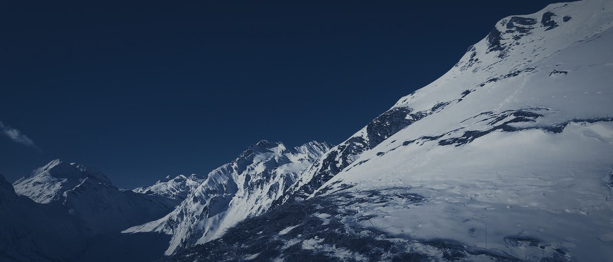 A snow-covered ridge at night rising to the right, distant peaks beyond.